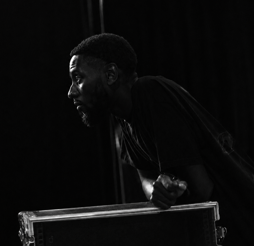 Black-and-white portrait of Eliud leaning over an equipment case.